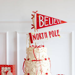 Decorative cake with 'Believe North Pole' sign on a white surface